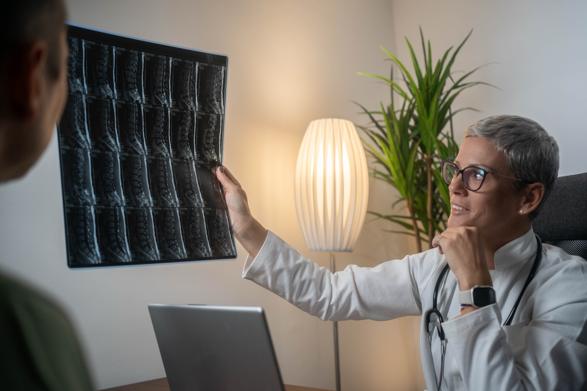 Physician holding a lumbar spine MRI up to the light while discussing the findings with a patient